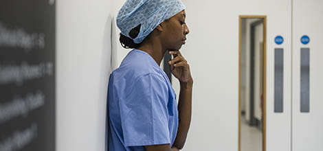 Side view of female doctor feeling concerned in scrubs standing in hospital corridor